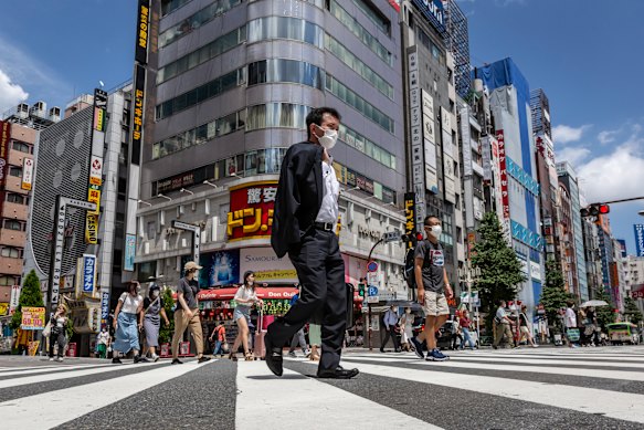 A masked-up Tokyo goes about its daily business. Community infections, unrelated to the Games, have surged.