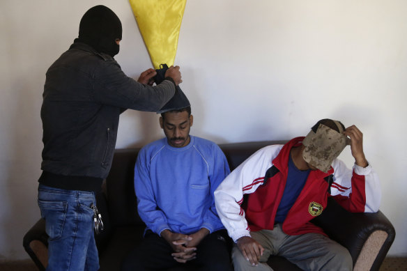A Kurdish security officer in 2018 removes face masks from Alexanda Amon Kotey (left) and El Shafee Elsheikh - allegedly among four British jihadis who made up a cell dubbed "The Beatles" - in Kobani, Syria. 