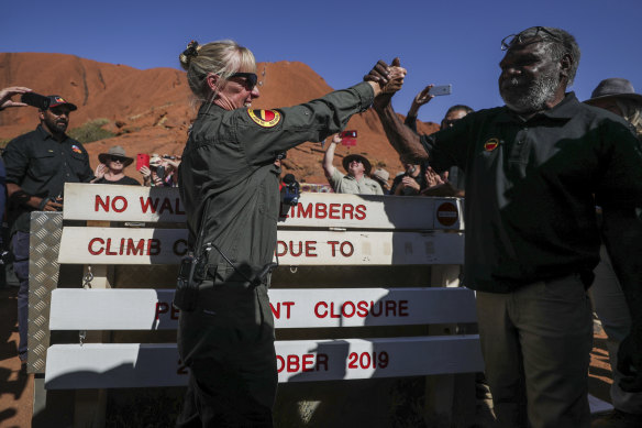 Ranger Lynda Wright celebrates with Chair of Uluru-Kata Tjuta national park, Sydney James, after placing the new sign of the permanent closure of the Uluru climb 