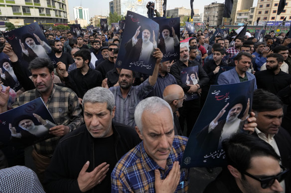 People hold up posters of Iranian President Ebrahim Raisi during a mourning ceremony for him in downtown Tehran, Iran.