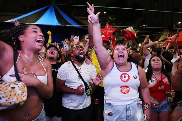 Supporters of  Lula da Silva react to the news of his win as the vote count plays out on a big screen.