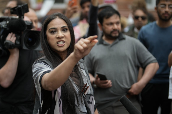 A woman speaks to the media as people gather outside the office of Manchester Metro Mayor Andy Burnham in the wake of a video showing a police officer kicking a man as he was being detained at Manchester Airport.