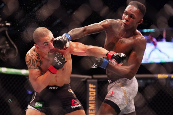 Robert Whittaker (left) is hit by Israel Adesanya (right) as they compete during UFC 243. 
