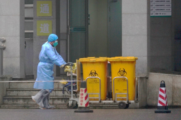 A staff member moves bio-waste containers past the entrance of the Wuhan Medical Treatment Centre in January 2020, the early days of the pandemic.