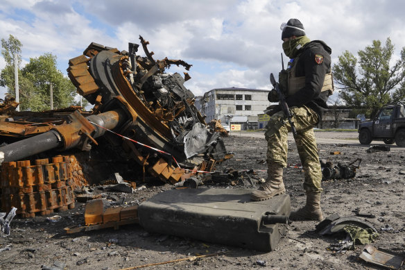 A Ukrainian soldier stands near a damaged Russian tank in Kupyansk in the Kharkiv region.