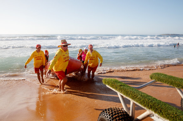 North Narrabeen SLSC Club patrol captain Adrian Hill (orange) and volunteers Graeme Jephcote (front) Jason Perry, Jacque Grimes, Jacinta Perry and John Beaumont return to shore on an inflatable rescue boat. 