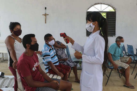 A health worker checks the temperature of the locals as she tests for COVID-19 at the Indigenous Park, a tribal community in the outskirts of Manaus, Amazonas state, Brazil.
