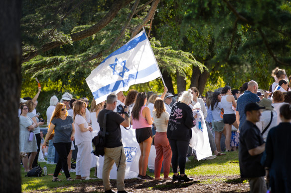 Attendees at the vigil at Hopetoun Gardens in Elsternwick hold an Israeli flag.