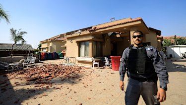 A policeman stands in front of a house hit by a rocket fired from Gaza Strip in Netivot, Israel.