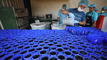 A volunteer fills cups for Venezuelan migrants at a migrant shelter in La Parada, near Cucuta, Colombia.