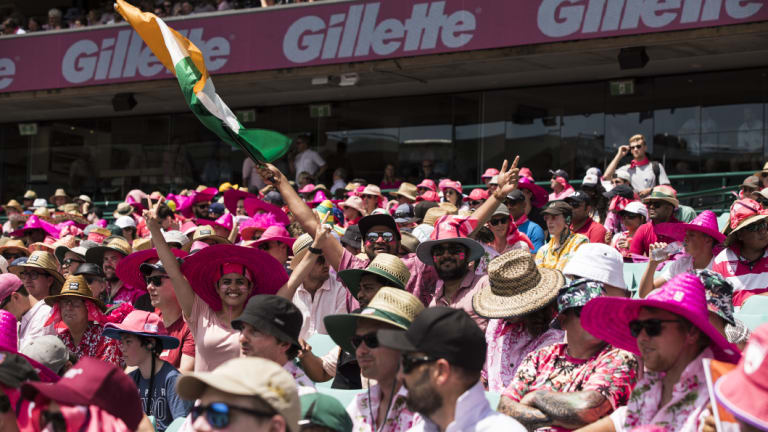 An Indian flag is raised among the pink shirts and hats in the stands on day three. 