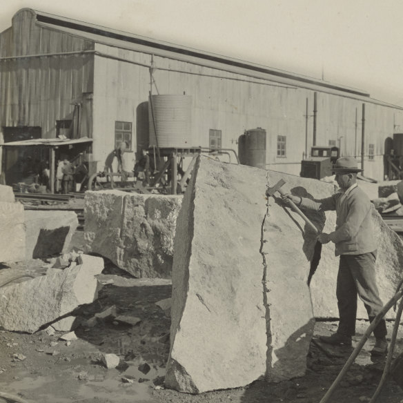 A worker splits the granite block with a plug and feather, a three-piece tool set.  