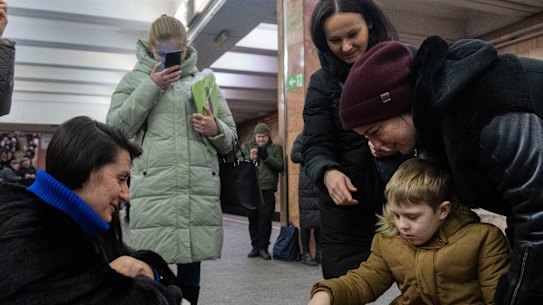 A boy and a woman play chess as other people watch in a subway station being used as a bomb shelter during a Russian rocket attack in Kyiv, Ukraine.