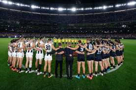 Carlton and Collingwood players, coaches and umpires form a circle as a show of support against gender based violence.