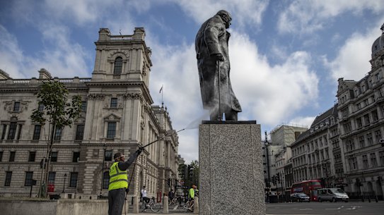 A worker cleans graffiti from the statute of former prime minister Winston Churchill.