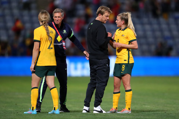 Coach Tony Gustavsson (right) consoles his Matildas players after the heavy loss to Spain.