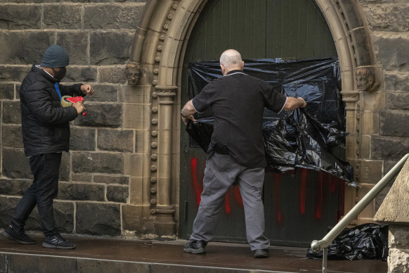 Workers cover graffiti at St Patricks Cathedral on Wednesday morning.