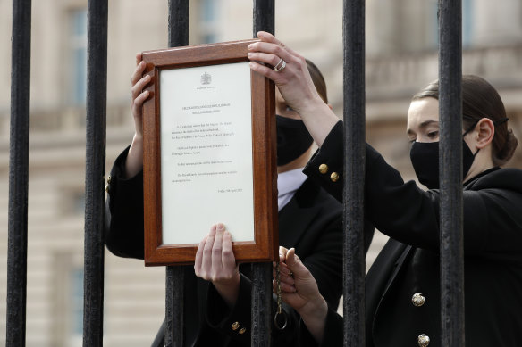 Palace staff attach the official announcement of Prince Philip’s death to the gates of Buckingham Palace.