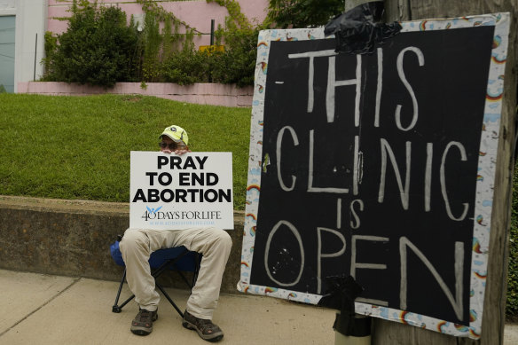 An anti-abortion supporter sits behind a sign that advises the Jackson Women’s Health Organisation clinic is still open in Jackson, Missouri.