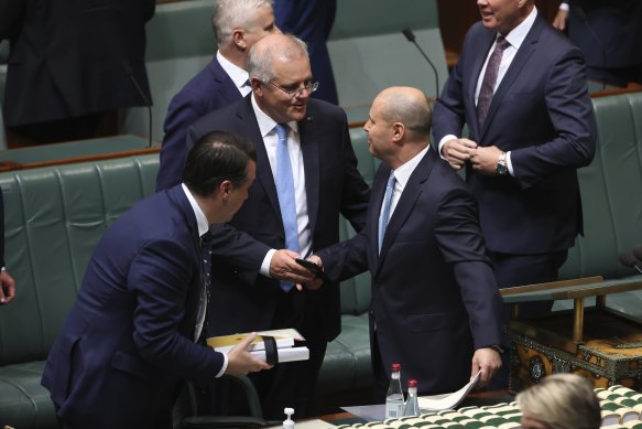 Treasurer Josh Frydenberg is congratulated by Prime Minister Scott Morrison and colleagues after delivering the budget speech.