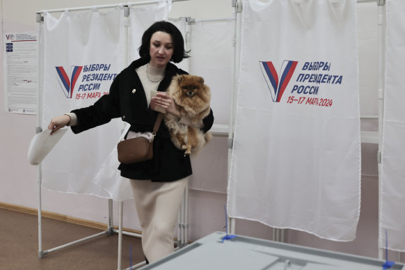 A woman holds her dog as she leaves a voting booth in the Pacific port city of Vladivostok.