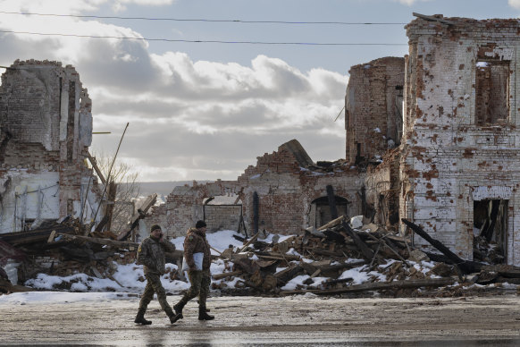 Ukrainian servicemen walk by a building destroyed by a Russian strike in Kupiansk on Monday.