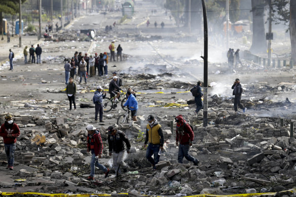 Pedestrians walk among the debris of barricades set by anti-government protesters in Quito on Sunday.
