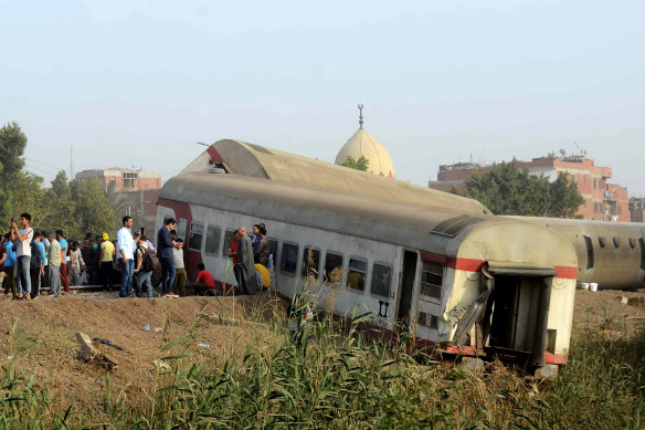 People gather at the site where a passenger train derailed injuring at least 100 people, near Banha, Qalyubia province, Egypt, Sunday, April 18, 2021. 