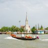 Traditional wooden boats cross the Mekong with Cai Be church in the background.