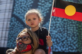 A young girl holds an Indigenous flag at the Invasion Day March in Sydney.