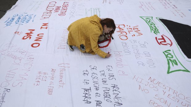 A woman writes a message on a protest poster during an anti-government demonstration in Bogota.