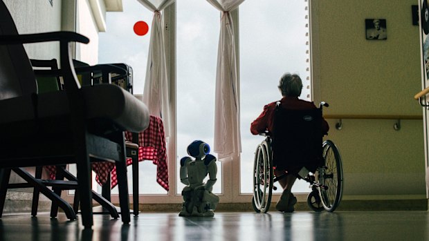 Zora squats beside a patient at Jouarre. The facility has seen some patients open up to the robot.