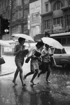 Three women run for cover on the corner of Swanston Street and Flinders Lane.