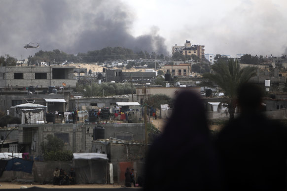 Palestinians watch an Israeli helicopter fly over Khan Younis, Gaza Strip.