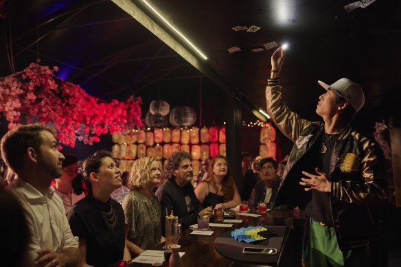 A magician entertains the crowd at the Maho Magic Bar as part of the Sydney Festival.