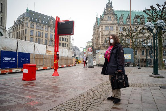 A commuter wears a protective mask on a deserted street outside city hall in Hamburg.