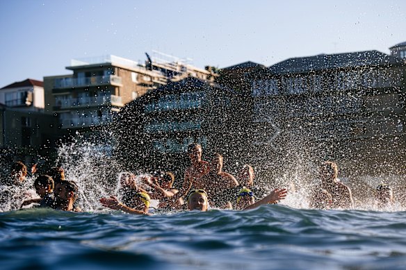 Swimmers and surfers splashing water and cheering in the ocean in the paddle-out.