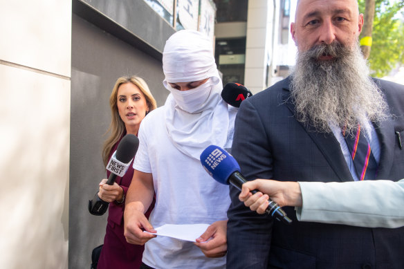 Journalists seek comment from Jack Gibson-Burrell as he leaves court with his face covered on Thursday.