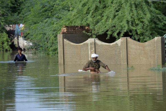 People wade through a flooded area in Jaffarabad, a district of Pakistan’s south-western Baluchistan province, late last month. 