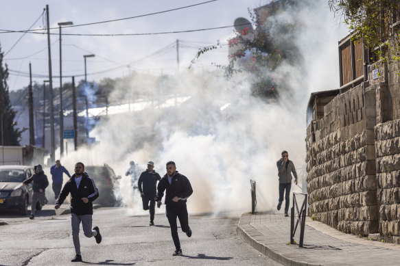 Palestinians run from tear gas fired by Israeli border police during Friday prayers along a road outside the Old City of Jerusalem, on December 22.