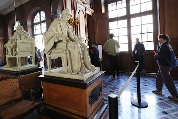 Loved coffee. People walk past a sculpture of Voltaire at the Richelieu Library in France.