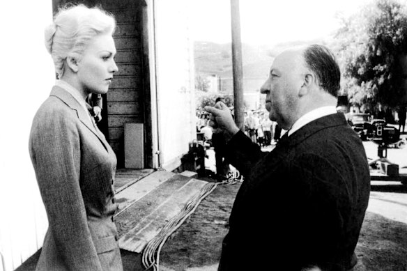 Kim Novak, in grey suit, on the set of Vertigo with director Alfred Hitchcock.
