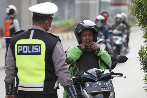 A police officer asks a man on a scooter to wear a face mask during the imposition of large-scale social restrictions in Jakarta, Indonesia.