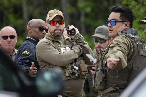 Authorities from multiple agencies work at a location where law enforcement believe they have cornered a suspect who allegedly shot and killed five people in a house the night before.