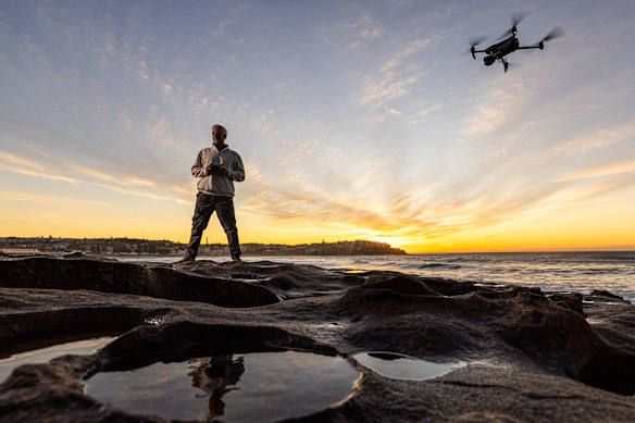 Jason Iggleden flying his drone on the rocks at the southern end of Bondi Beach.
