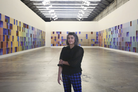 Artist Kate Mitchell stands in front of her installation, which she's still completing as she hunts down photographic subjects with obscure occupations. 