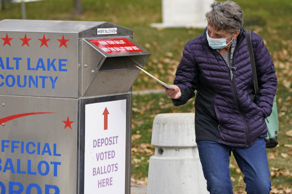 A woman inserts her ballot at a drop box in Salt Lake City.