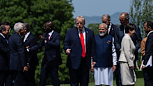 Donald Trump stands alone as other world leaders chat with each other.