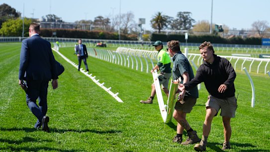 Ground staff move running rails at Caulfield on Saturday to avoid a dangerous stretch of the track.