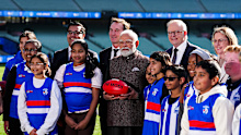 Prime Minister of India Narendra Modi poses holding a Sherrin alongside AFL CEO Andrew Dillon, Prime Minister of Australia Anthony Albanese, Victorian Premier Jacinta Allan and young footballers.